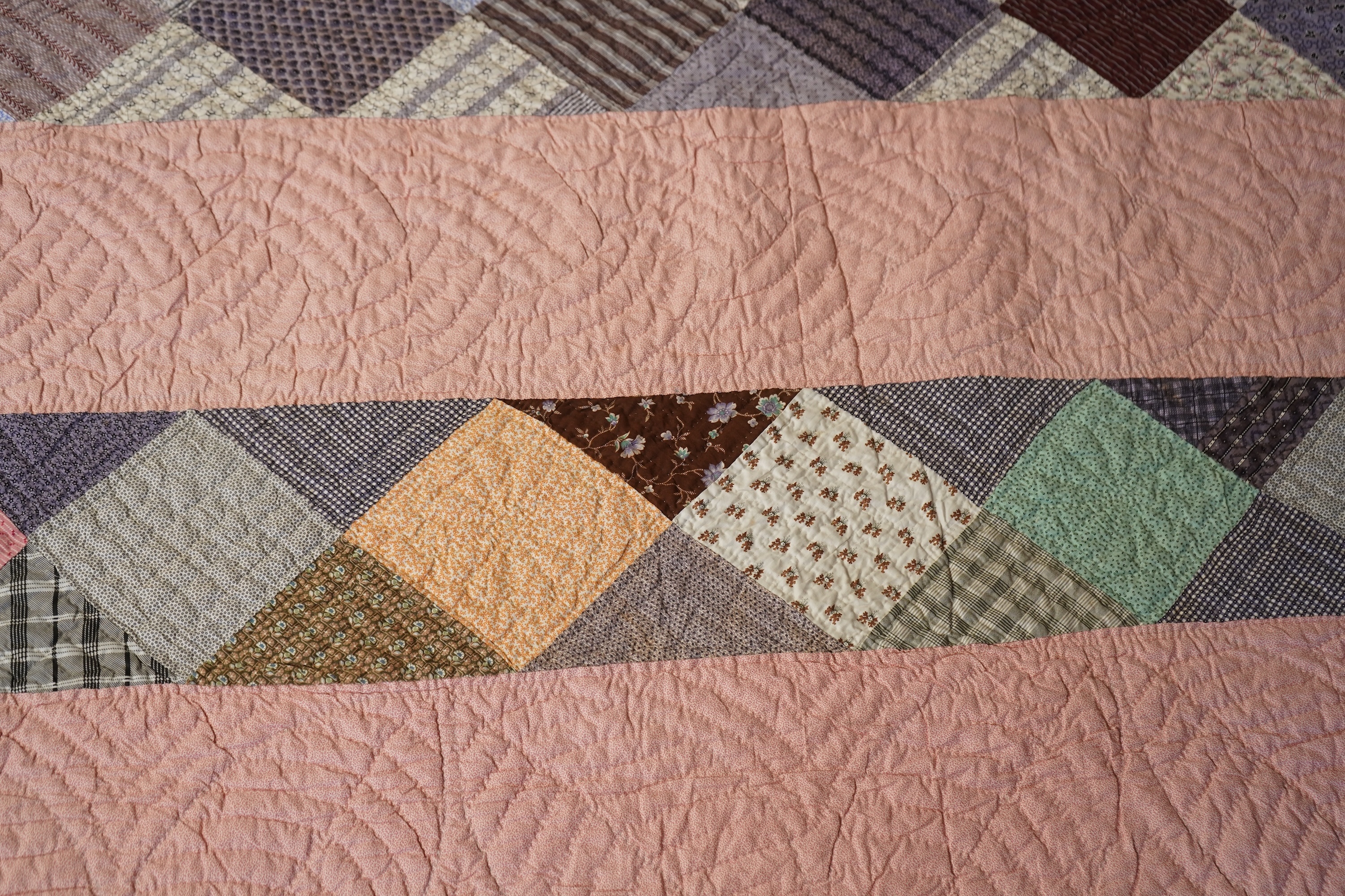 A late 19th century English, possibly ‘North Country’ cotton, hand quilted bed cover. Worked in stripes, with alternate patch worked stripes of differing colour fabrics. Made from fashionable cotton fabrics of the era. R